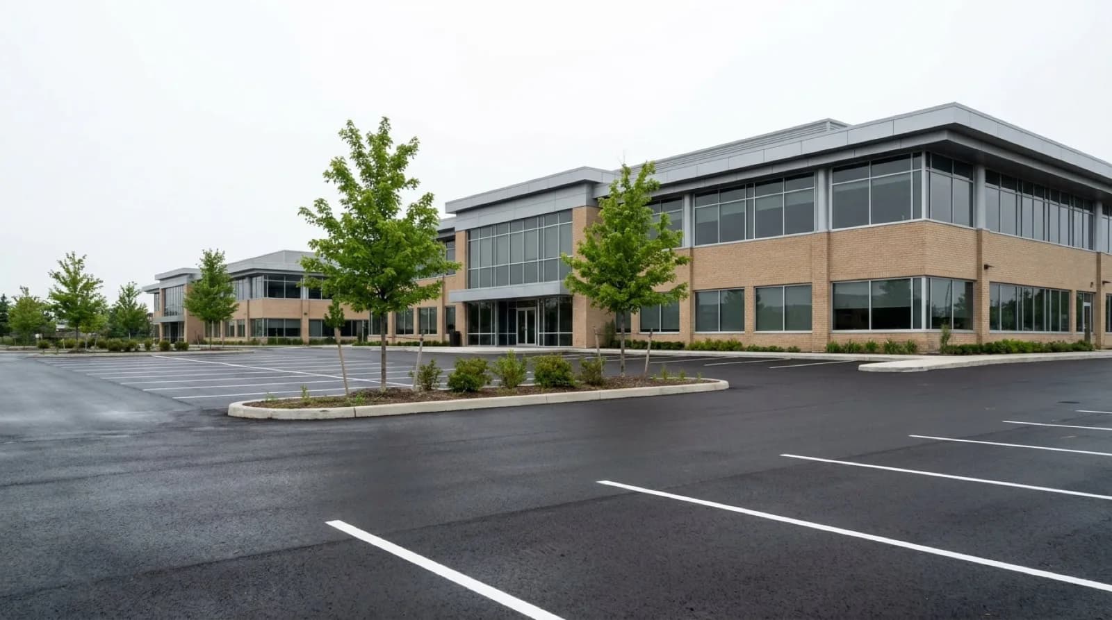 A freshly paved and lined commercial parking lot behind a low office plaza in the Greater Toronto Area.